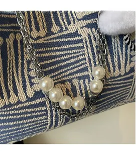 Detail of silver metal chain with white pearls on a blue jacquard woven tote bag