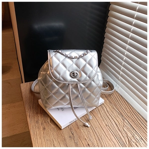 Close-up of silver quilted mini backpack with metallic finish and chain handle on desk