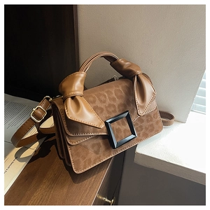 Detailed close-up of leopard print handbag with matte square buckle and knotted handle