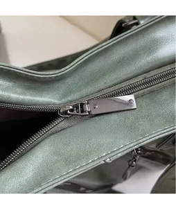Dettaglio della cerniera in metallo lucido di questa borsa da viaggio verde vintage