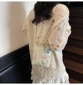 Close-up of small canvas crossbody bag with delicate flower and butterfly embroidery detail