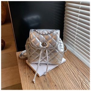 Close-up of silver quilted backpack featuring metallic finish and turn-lock detail