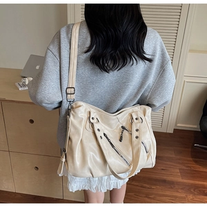 Dettaglio di una grande borsa beige con tracolla che mostra la trama in morbida pelle PU