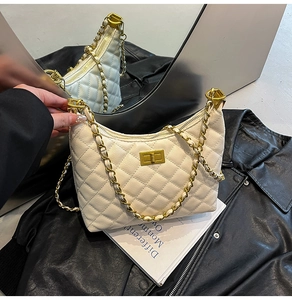 Detail of beige quilted shoulder bag with gold chain strap and turn-lock closure