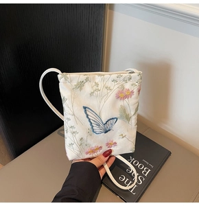 Detailed view of floral embroidery featuring blue butterflies and pink daisies on bag