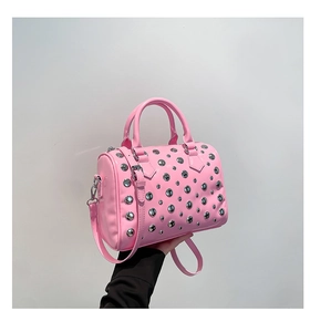 Detail of pink patent leather Boston bag featuring dense silver rivets and dual top handles