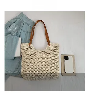 Close-up of beige woven tote bag showing mesh texture and brown leather handles with rivets