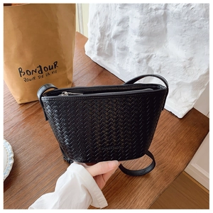 Detail of black woven leather bucket bag with metal zipper and premium textured finish