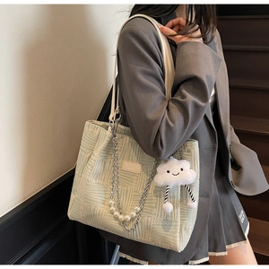 Detail of light green knit tote with pearl chain strap and plush cloud charm accent