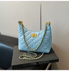 Detailed shot of light blue quilted leather bag with gold twist lock on black books