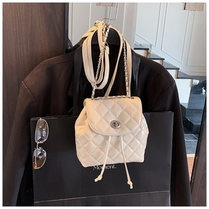 Detail of cream quilted mini backpack with silver chain strap and metal turn-lock