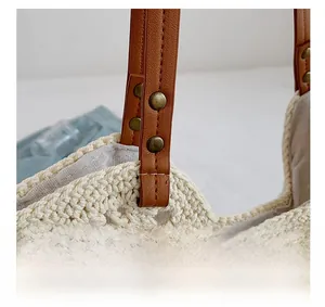Detail of woven tote bag featuring brown leather handle and vintage bronze rivet fasteners