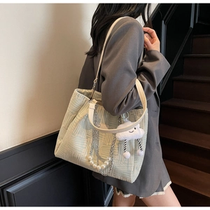 Detail of light green quilted tote bag with pearl chain and cloud plush charm
