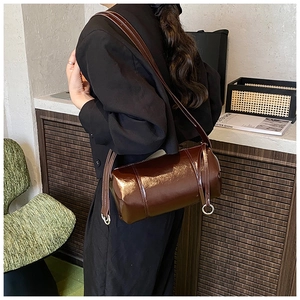 Detail of vintage cylindrical shoulder bag in dark brown glossy leather with metal rings