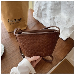 Close-up of brown woven texture bucket bag with crossbody strap and zipper closure