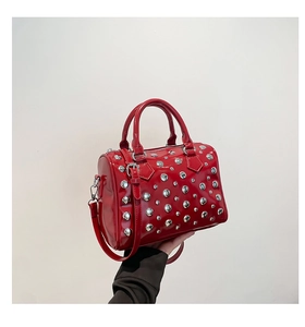 Detail of red patent leather handbag with silver studs and adjustable shoulder strap