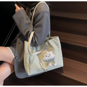 Detail of light green tote with white patterns, pearl chain, and cloud charm on stairs