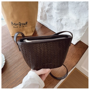 Detailed close-up of dark brown woven leather bucket bag with brand logo and zipper