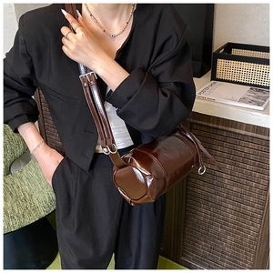 Detail of dark brown retro cylinder bag with glossy leather and adjustable strap