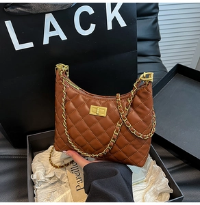 Detail of brown quilted leather bag with vintage gold turn-lock and chain strap