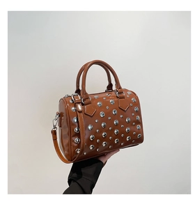 Detail of brown glossy Boston bag with silver rivets and adjustable shoulder strap