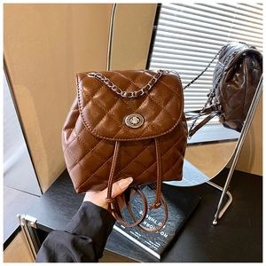 Detail of dark brown quilted leather backpack with metal twist lock and chain handle