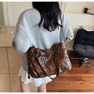 Detailed back view of a dark brown vintage oversized tote bag with metal rivets and zippers