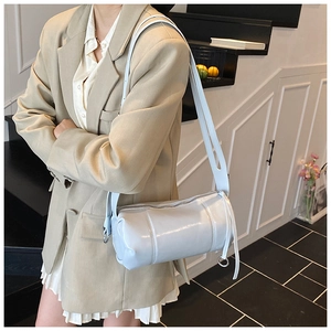 Detail of adjustable cutout shoulder strap and metallic buckle on light blue cylinder bag