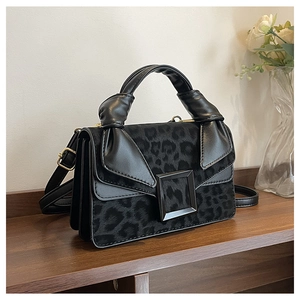 Detail of leopard print crossbody bag featuring a unique twisted leather handle and buckle