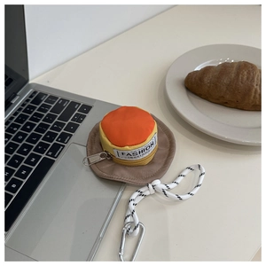 Macro view of a mini hat-shaped pouch with a metal carabiner on a desk lifestyle scene