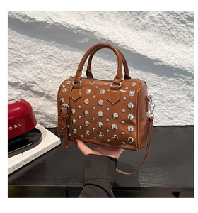 Detail of a brown glossy leather Boston bag with silver rivets and top handles