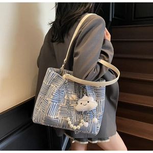 Detail of canvas tote bag with geometric blue patterns, fluffy cloud charm and pearl chain