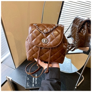 Detail of dark brown quilted backpack featuring chain handle and metal twist lock