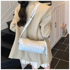 Detail of cream retro cylinder shoulder bag with glossy finish and silver hardware accents