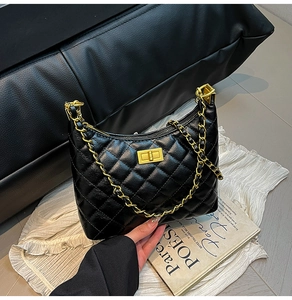 Close-up of black quilted leather texture with gold metal chain and rectangular lock