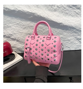Pink patent leather Boston bag with silver studs held by hand for a stylish look