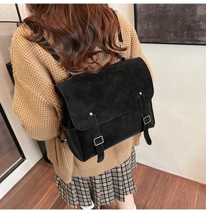 Close-up of vintage black matte backpack with leather straps on a model in a cozy sweater