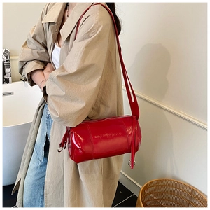 Detail of red cylindrical shoulder bag in glossy patent leather with zipper closure