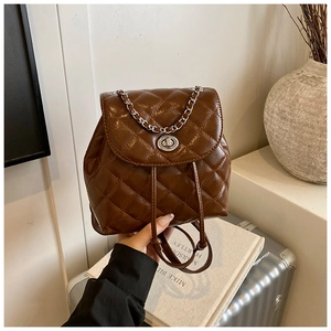 Detail of quilted dark brown backpack featuring silver chain handle and metal twist lock