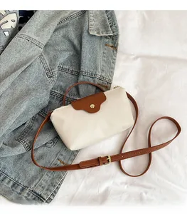 Detail of nylon crossbody bag with brown leather flap and golden button closure