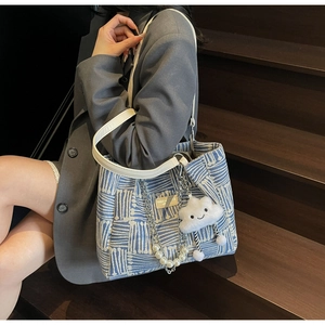 Detail of blue geometric woven tote bag with pearl chain and cloud pendant charm