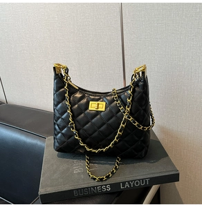 Detail view of black quilted hobo bag with gold chain strap and square metal buckle