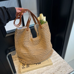 Detail of woven mesh tote with brown leather strap and rivets on marble background