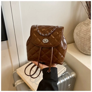 Detail of dark brown quilted backpack with silver chain and metallic turn-lock closure