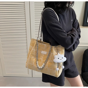 Detail of yellow canvas tote bag with pearl chain decoration and plush cloud charm