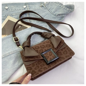 Detail of leopard print crossbody bag with black buckle and bow handle on denim