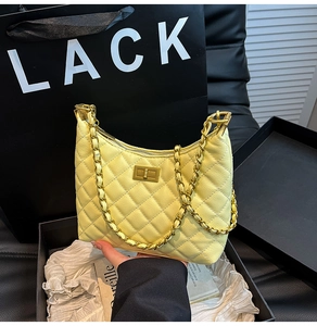 Detailed view of yellow quilted leather bag with gold chain strap and twist lock closure