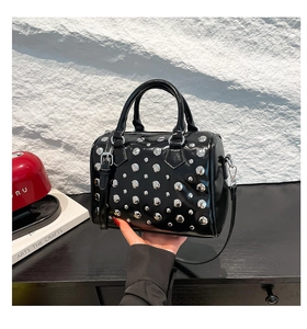 Detail of black patent leather Boston bag featuring silver studs and dual top handles