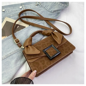 Detail of leopard print crossbody bag with knot handle and square buckle on denim