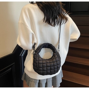 Détail d'un sac matelassé noir sur modèle affichant des motifs de couture carrés modernes